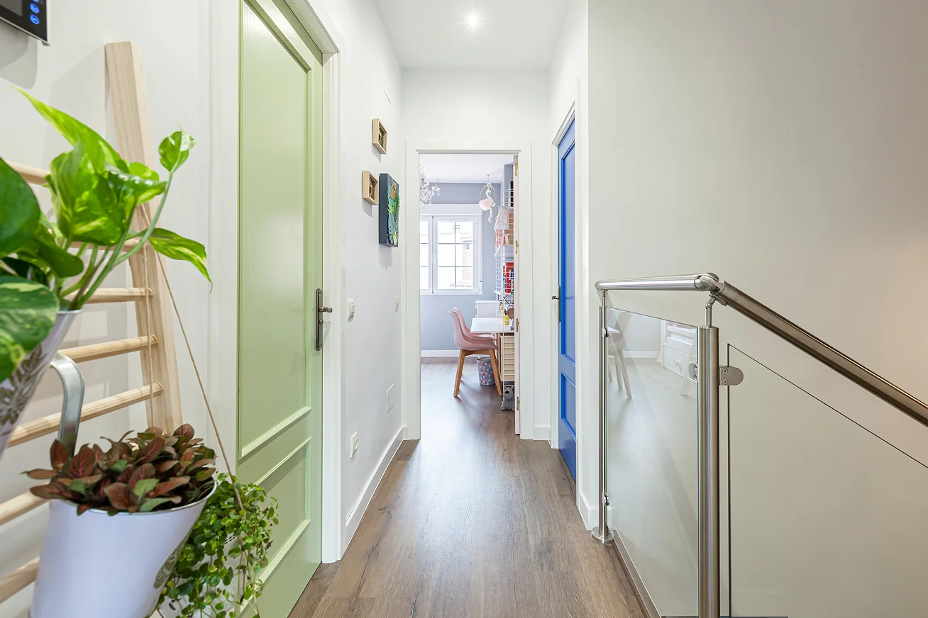 Sinpar Studio — Pasillo con puertas colores y barandilla cristal reforma chalet Toledo