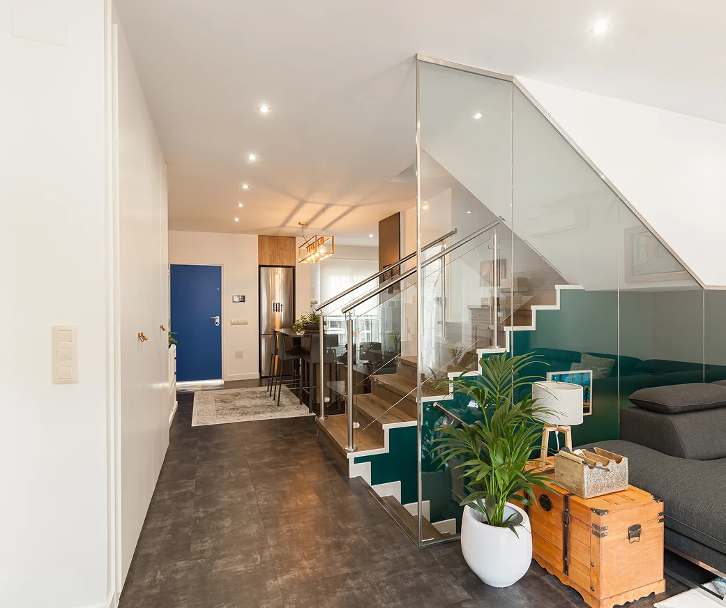 Sinpar Studio — Recibidor con puerta azul y escalera cristal reforma chalet Toledo
