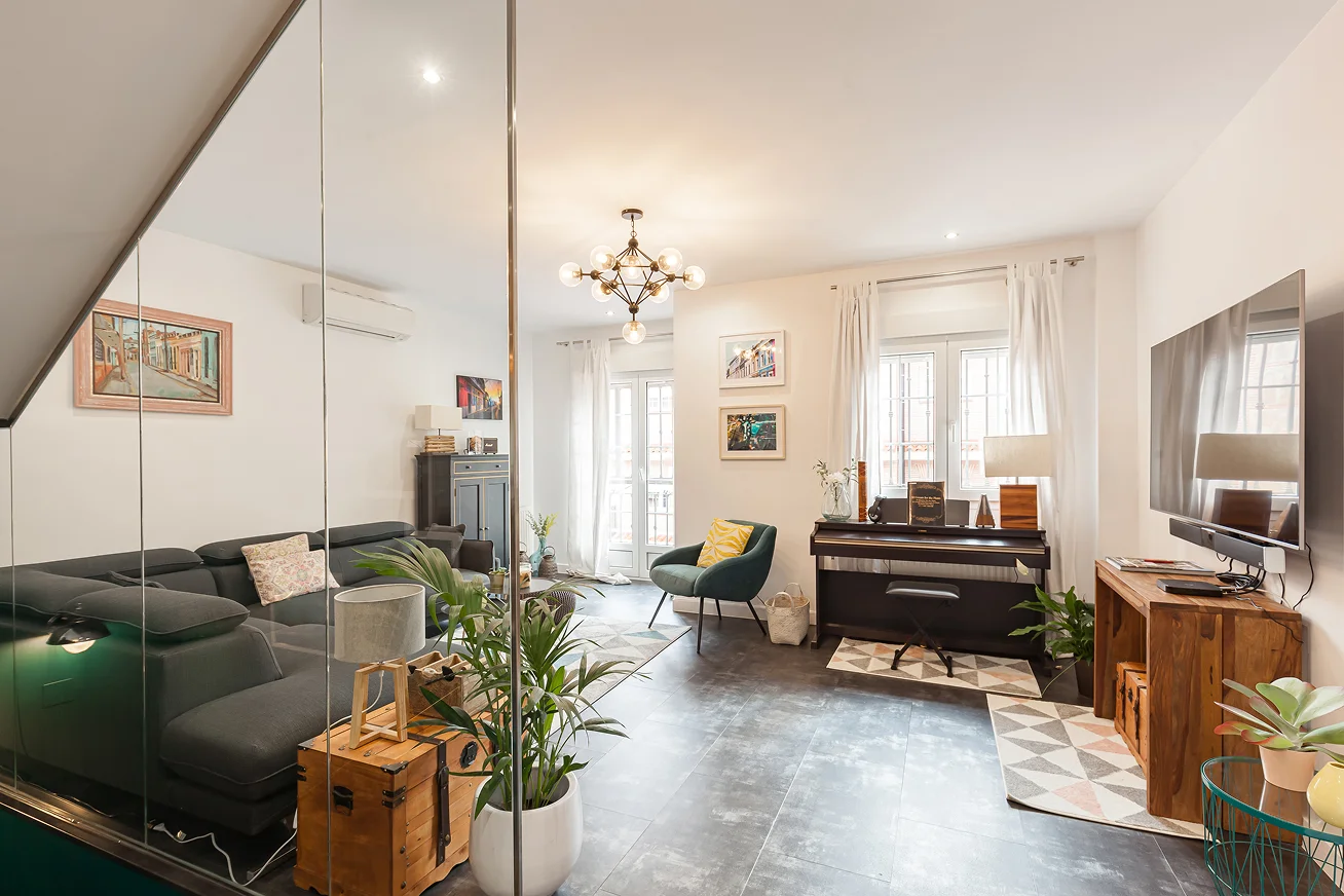 Sinpar Studio — Salon con sofa gris y piano visto a traves del cristal reforma chalet Toledo